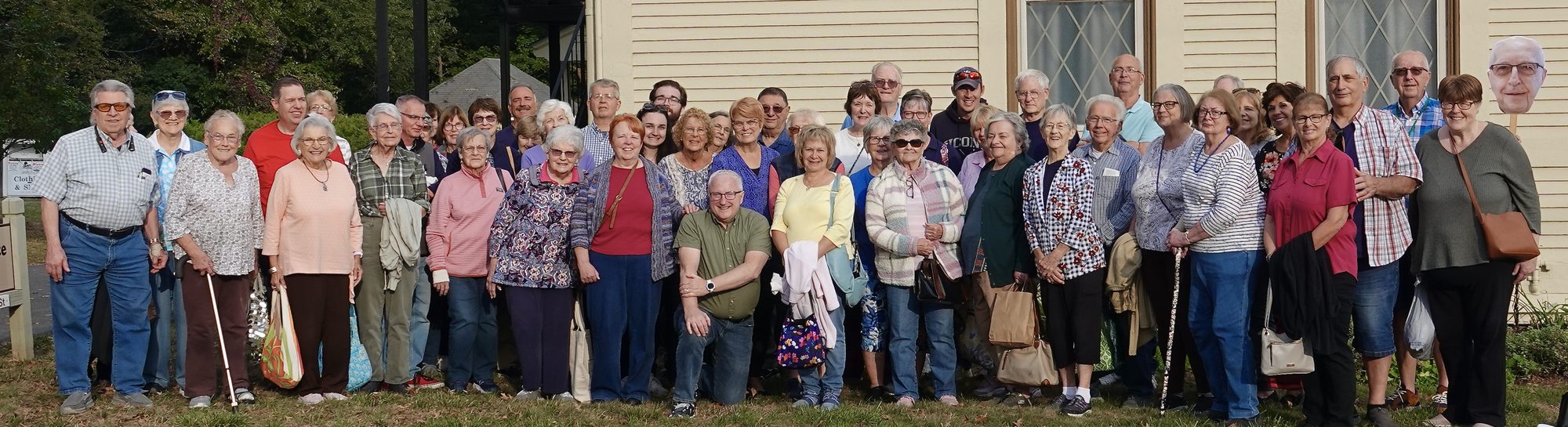 A large group of church members standing together on the lawn beside the church