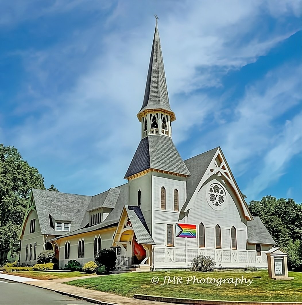 Plantsville Congregational Church from the street: light brown clapboard, a tall spire, and the rose window