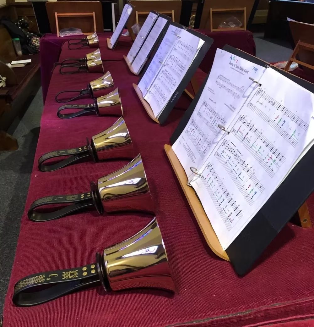 Handbells and sheet music laid out on a red cloth for rehearsal