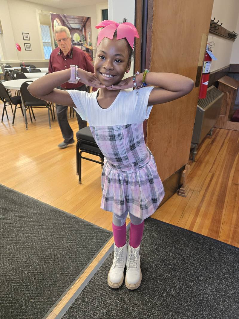 A child in pink sunglasses posing proudly in Fellowship Hall