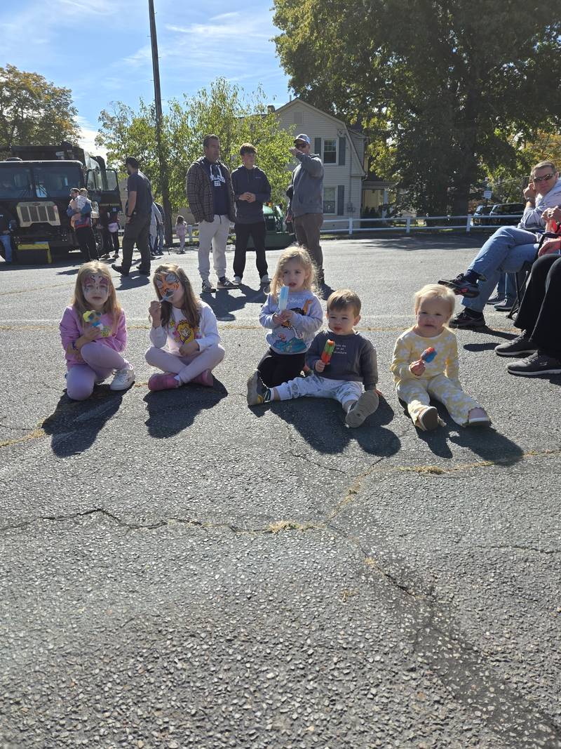Children sitting together on the pavement eating popsicles at a church event