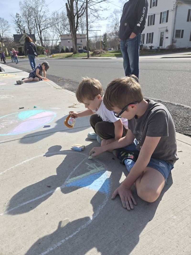 Two children drawing with sidewalk chalk outside the church